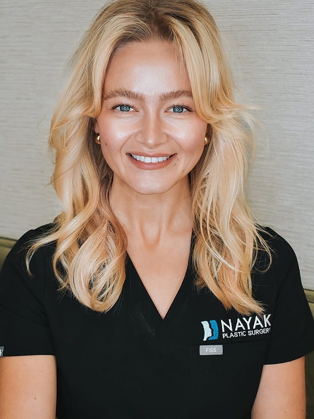 Smiling professional in plastic surgery scrubs.