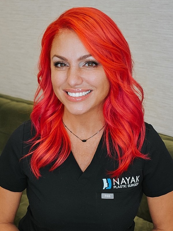 Woman with vibrant red hair smiling in scrubs.