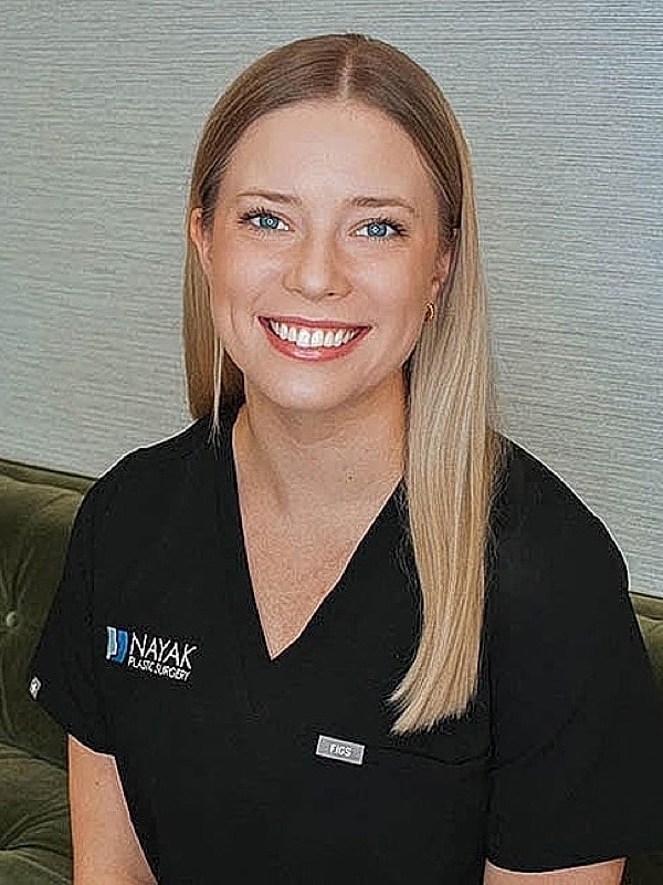 Smiling woman in medical attire at clinic.