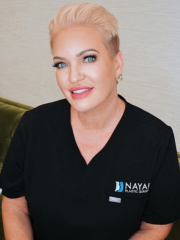 Woman in scrubs smiling at the camera.