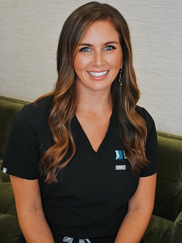 Smiling woman in scrubs sitting on a sofa.