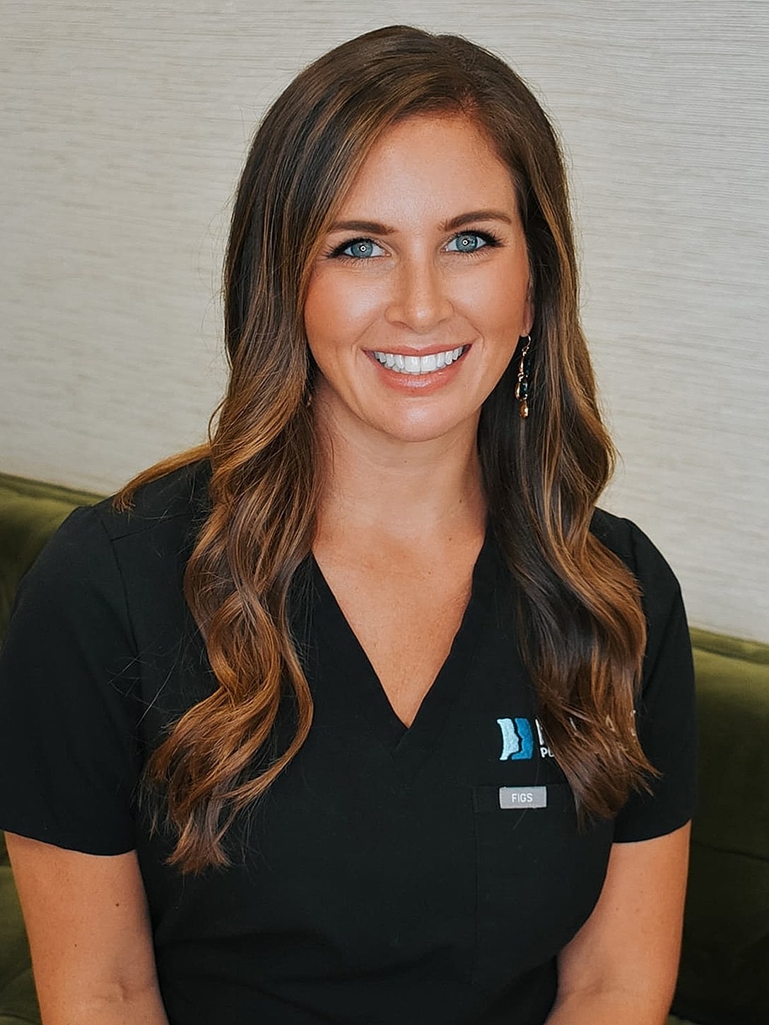 Smiling woman in medical scrubs, professional setting.