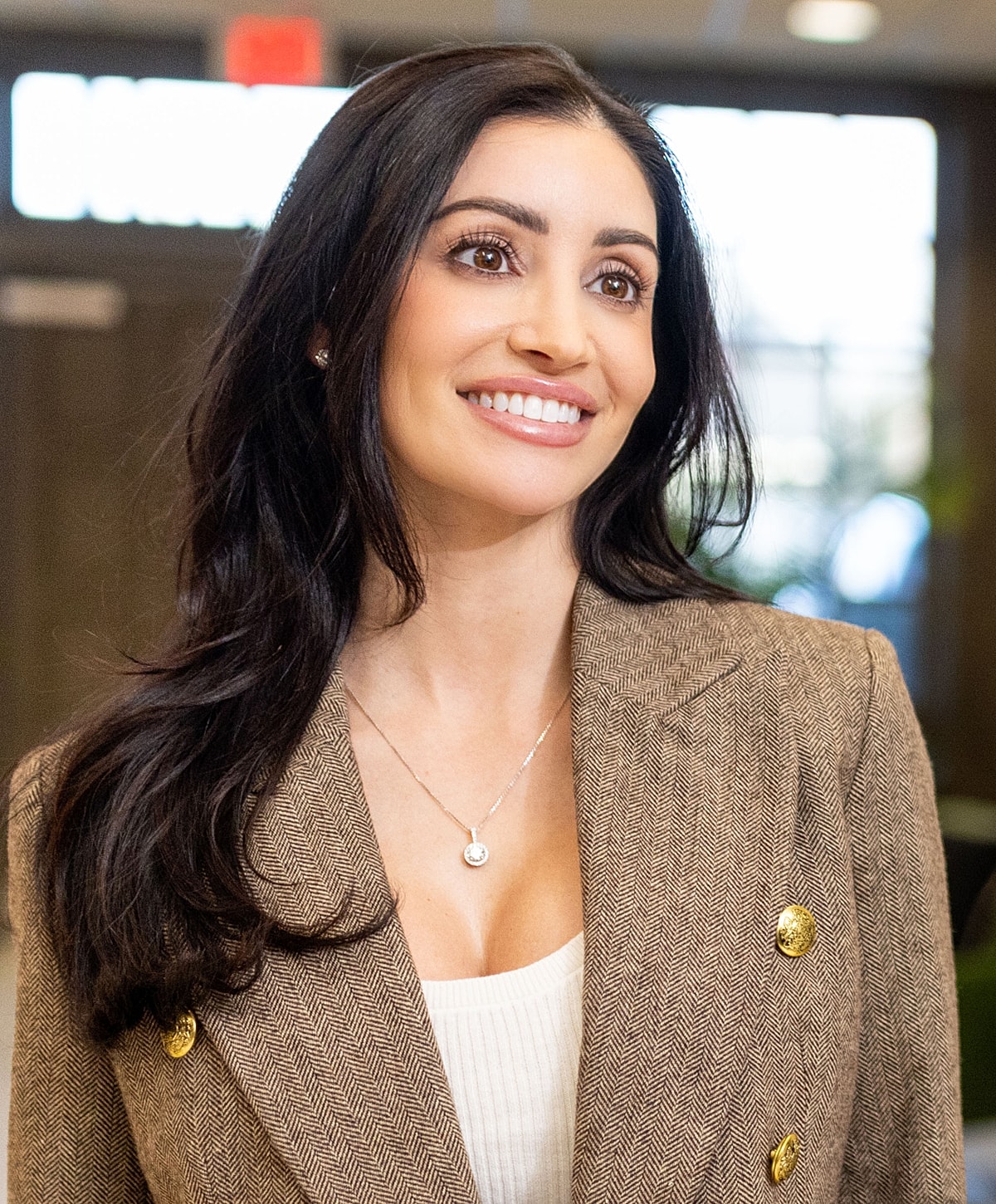Woman smiling in a stylish blazer indoors.