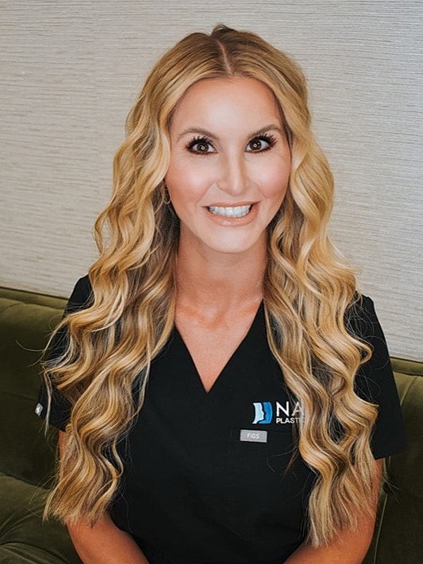 Smiling woman in black scrubs with curly hair.