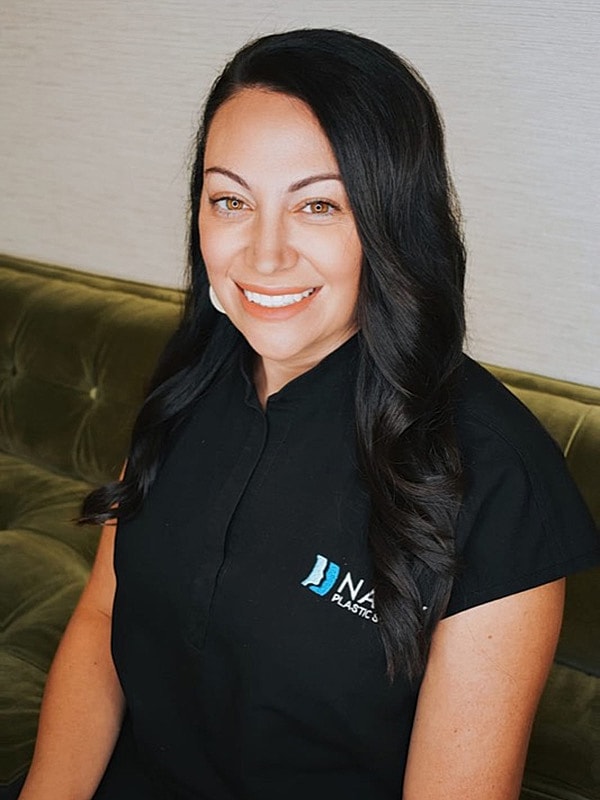 Smiling woman in professional attire, sitting indoors.