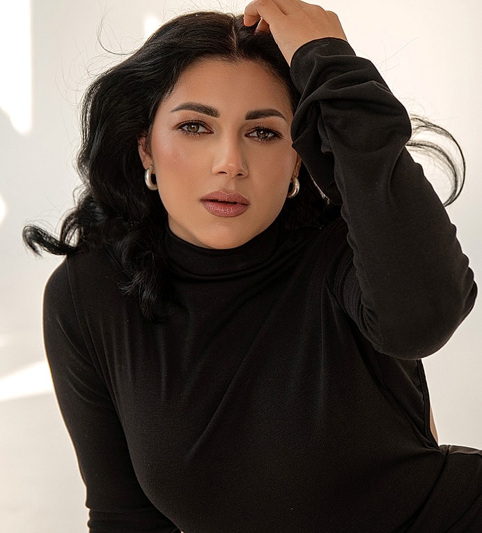 Woman with dark hair in a black turtleneck.